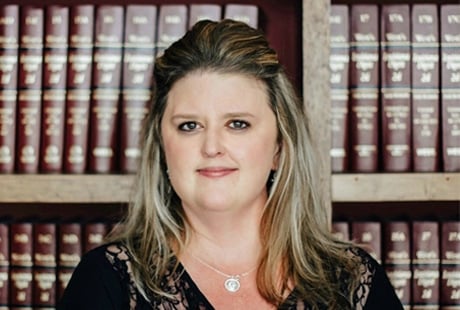 Woman smiling in front of bookshelf filled with law books.