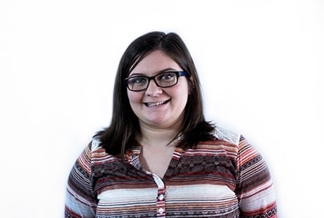 Smiling person with glasses wearing a striped shirt against a plain white background.